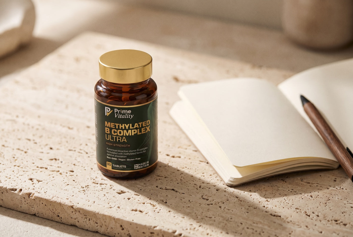 Prime Vitality Methylated B Complex Ultra bottle on a travertine surface beside a notebook